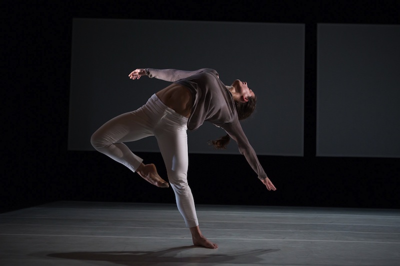 A female dancer suspends backwards on one leg with other leg in passe, her upper body lifts towards the heavens